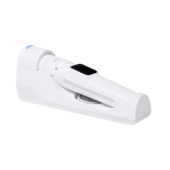 White handheld medical device with a curved body and black touchscreen, resting on a white base.