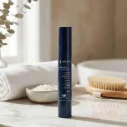 Blue bottle of skincare product standing upright on a marble bathroom counter, with a towel and a brush in the background.