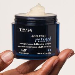 Blue jar of IMAGE Skincare AgeLess+ Retinol overnight masque with creamy white product visible at the top, held between two hands. Best for conveying skincare product use and packaging.