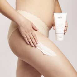 Person applying cellulite-firming body cream to their thigh from a white tube labeled 'Body Spa'