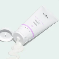 Tube of body lotion labeled 'Body Spa' with a lavender accent, cap open and lotion squeezed in a wavy line on a pale mint background.