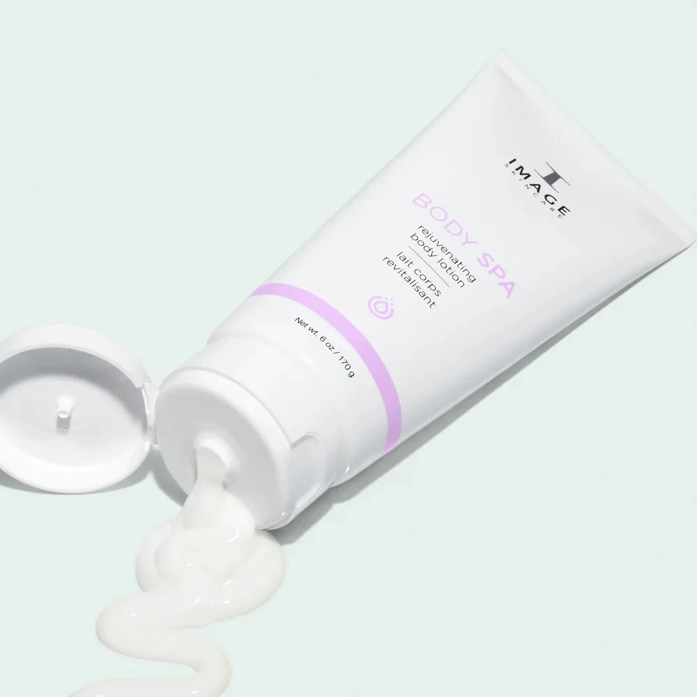 Tube of body lotion labeled 'Body Spa' with a lavender accent, cap open and lotion squeezed in a wavy line on a pale mint background.