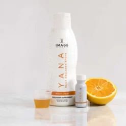 White skincare bottles with orange accents beside halved oranges on a marble surface, minimal backdrop.