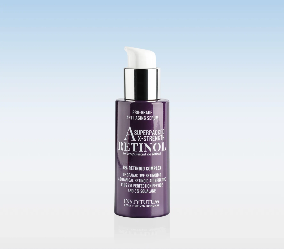 Purple pump bottle of retinol serum on a white surface with a blue gradient background, front label visible and legible.