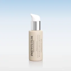 Beige skincare bottle with white pump dispenser and silver collar against a soft blue gradient background.